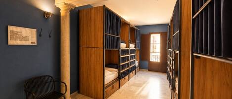 Habitación de hotel con cama, armario de madera, una silla y un mapa en la pared.