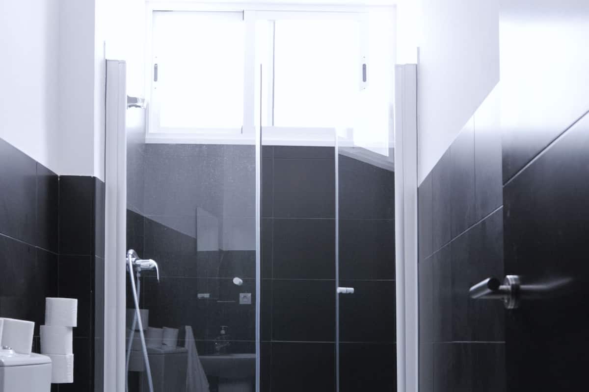 Un baño moderno con ducha envuelta en vidrio, inodoro y lavamanos.