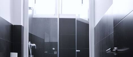 Une salle de bain moderne avec une douche à parois de verre, des toilettes et un lavabo.