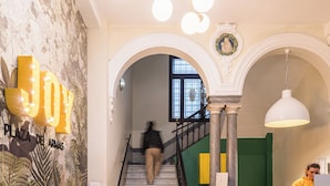 Vestíbulo de hotel con suelo de cuadros, una escalera y una recepción.