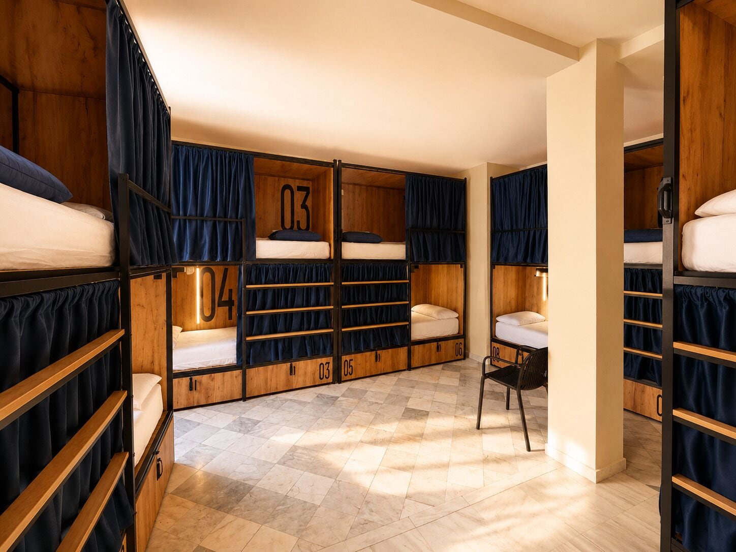 A dormitory room with bunk beds, a chair, and a tiled floor.