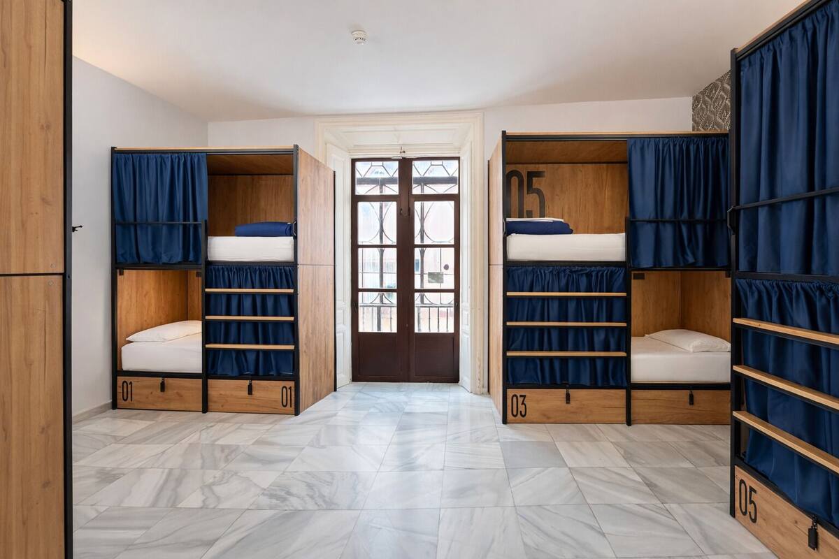 Un dormitorio con literas, compartimentos numerados para guardar objetos y vistas a través de una puerta de vidrio.