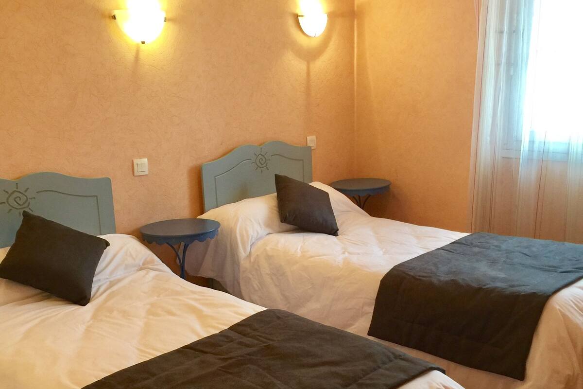 A hotel room with two beds, each with a headboard and pillow, and a small table beside each bed.