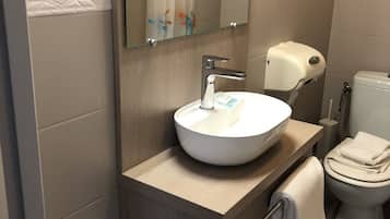 Un baño moderno con un lavamanos blanco, un espejo, un inodoro y un perchero para toallas.