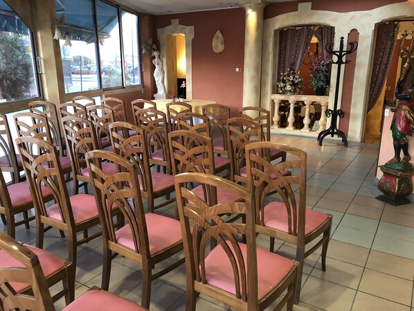 Un comedor con sillas y mesas de madera, una estatua y un adornado muro.