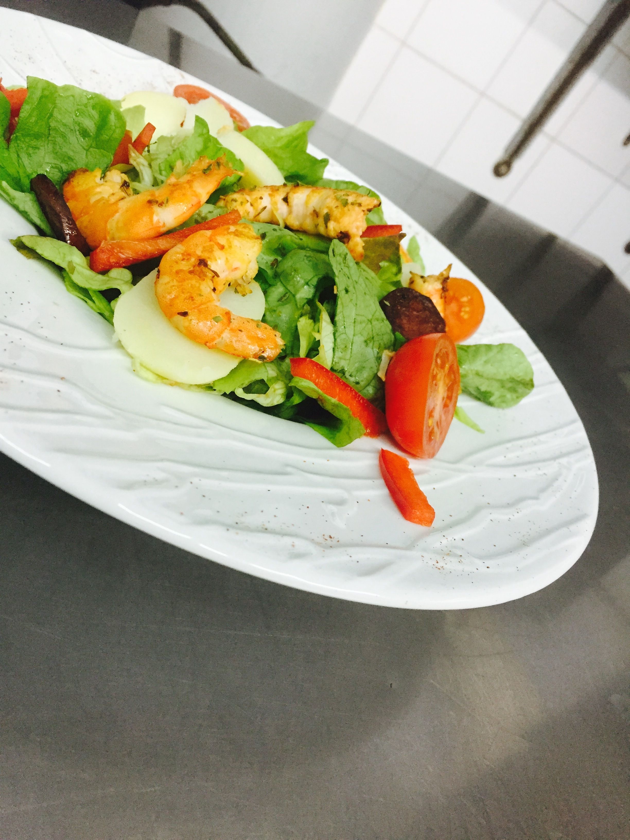Een bord garnetonsalade met sla, tomaten en andere groenten.