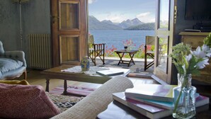 Een gezellige woonkamer met uitzicht op een meer en bergen.
