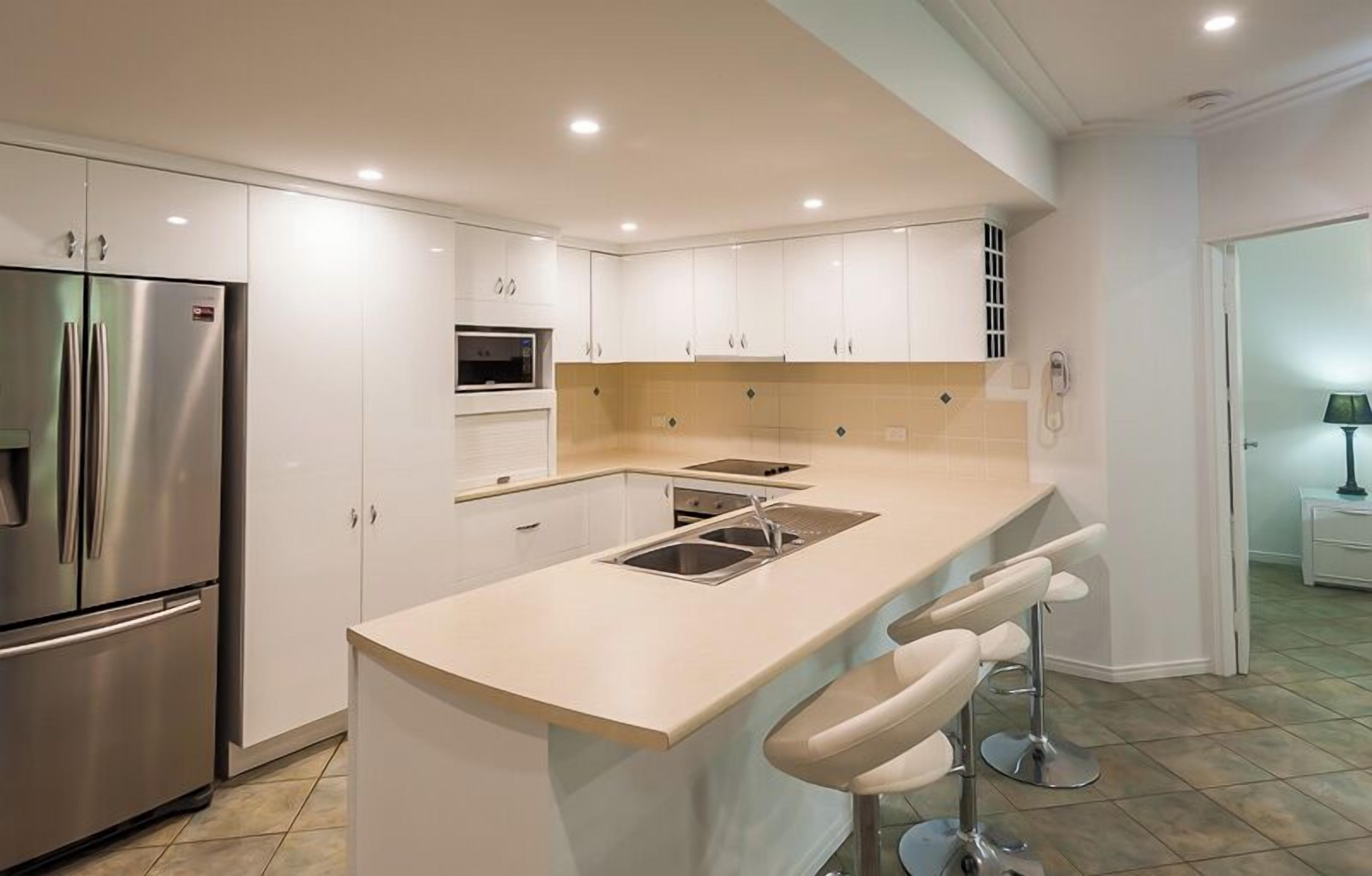A modern kitchen with white cabinets, stainless steel appliances, and a central island with bar stools.