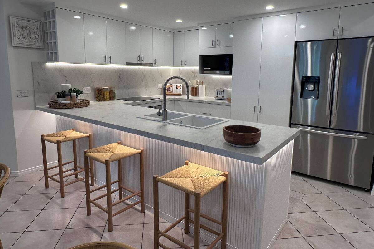 A modern kitchen with a central island, stainless steel appliances, and a built-in TV.