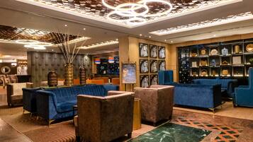 A modern lobby with sofas, a decorative ceiling, and a display of handbags.