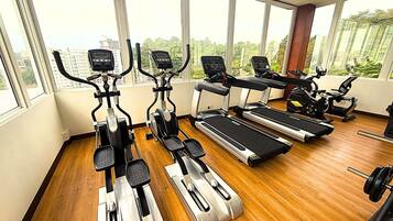 A gym with cardio equipment, including treadmills and elliptical machines, and a weight bench.