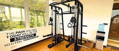 Un gimnasio con barra de dominadas, máquina de pesas y una frase motivacional en la pared.