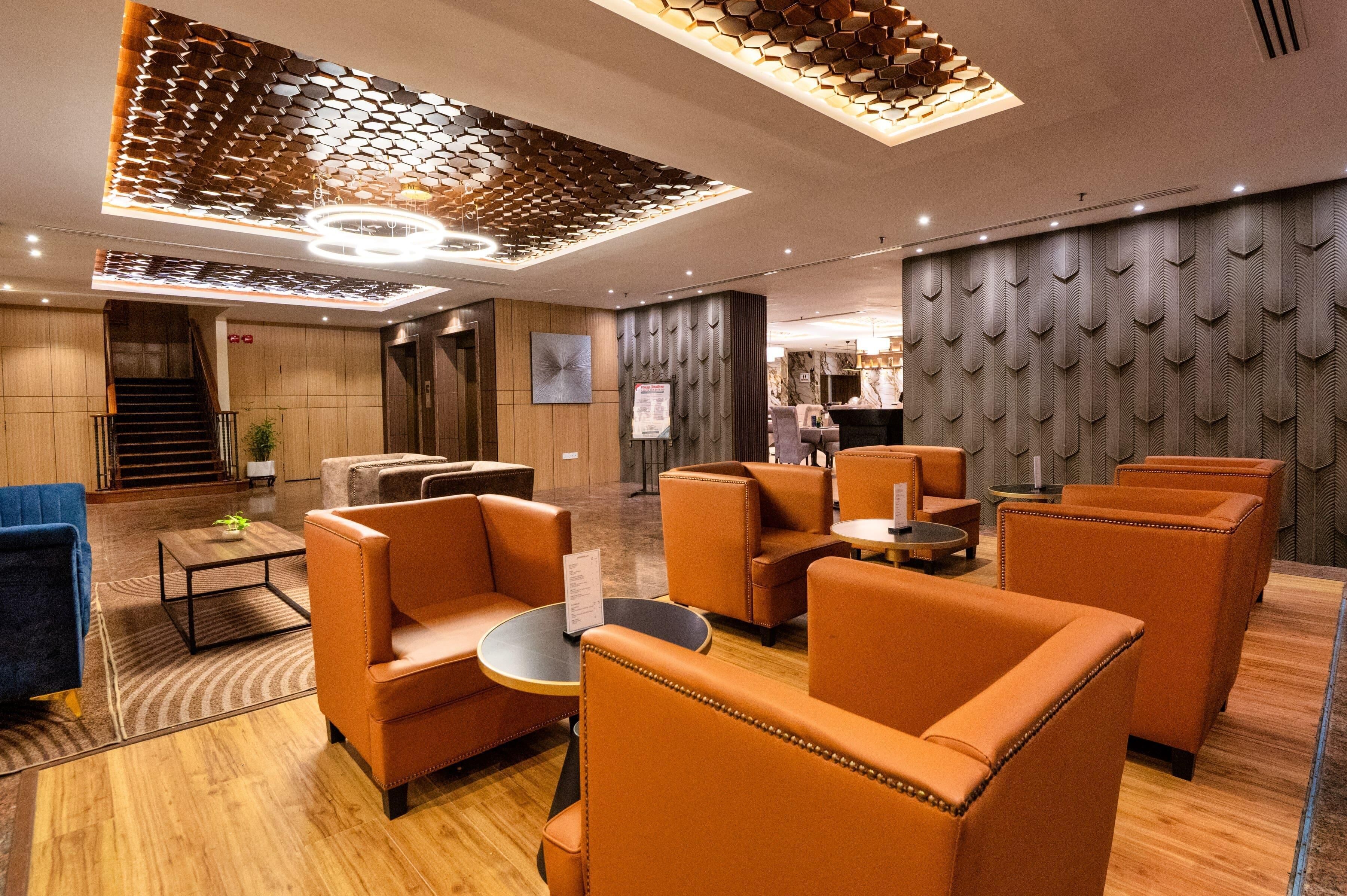 A modern lounge area with leather sofas, a wooden floor, and a unique ceiling design.