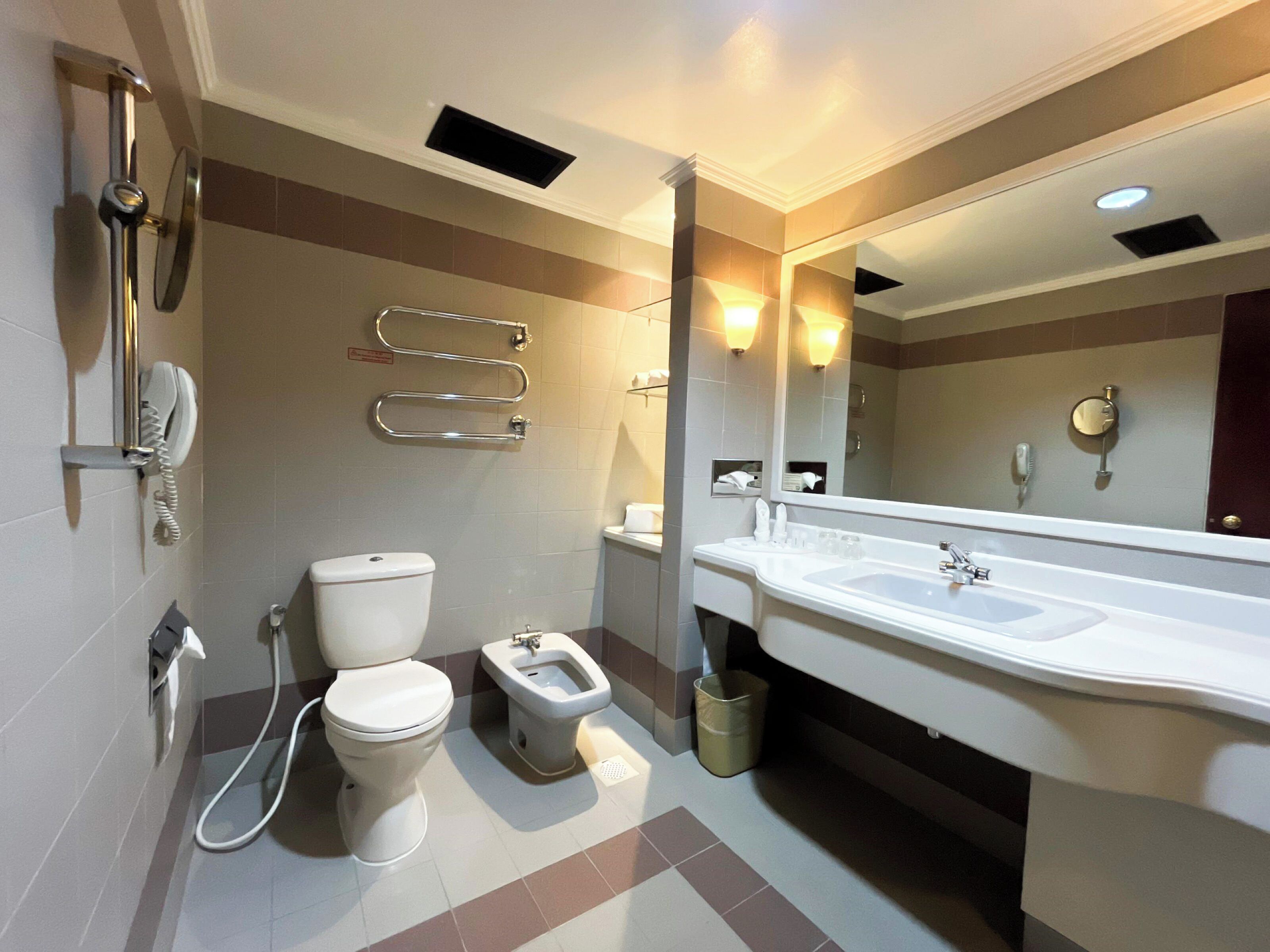 A modern bathroom with a toilet, bidet, and a large sink.