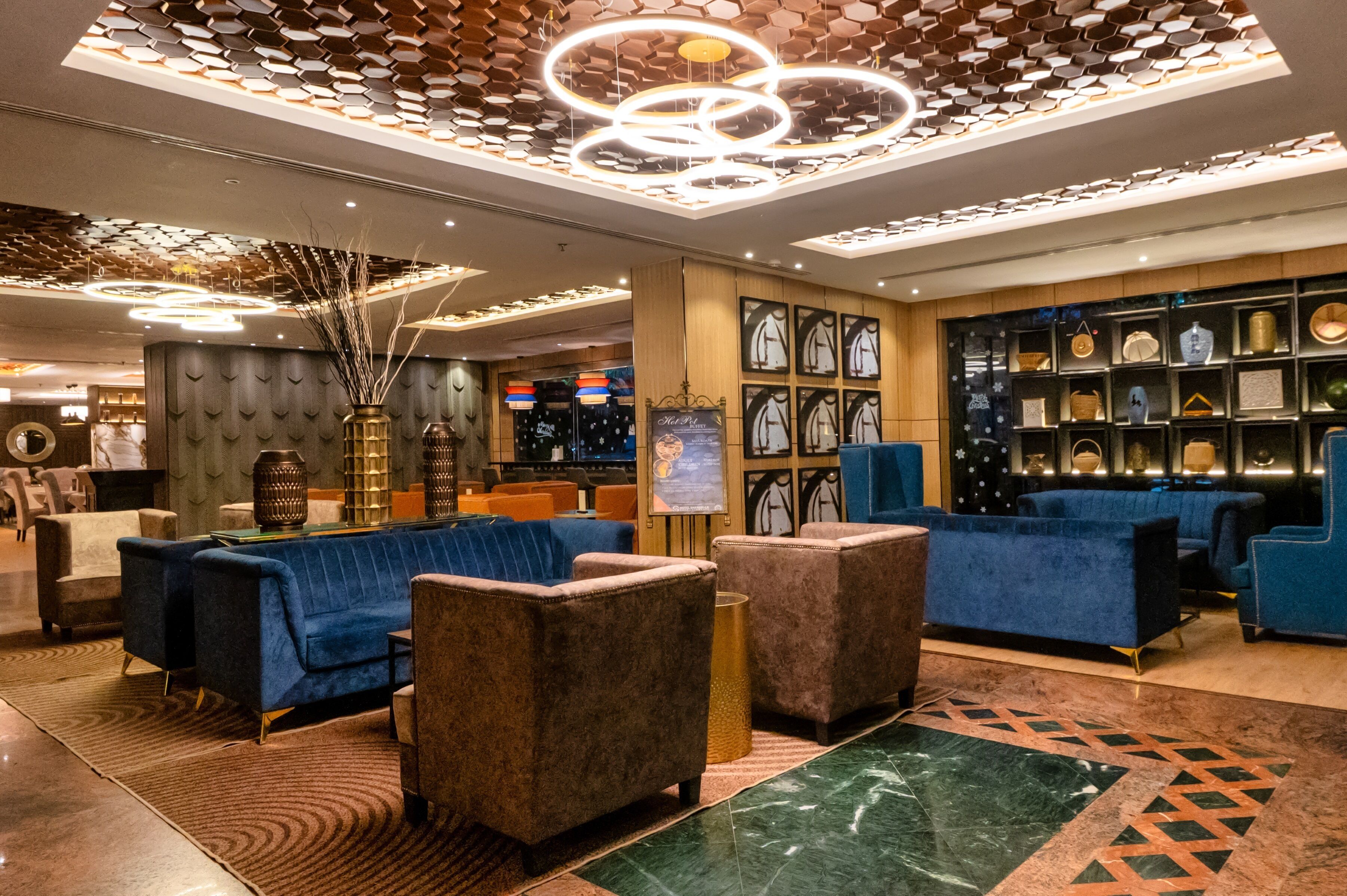 A modern lobby with blue sofas, a marble floor, and a decorative ceiling.