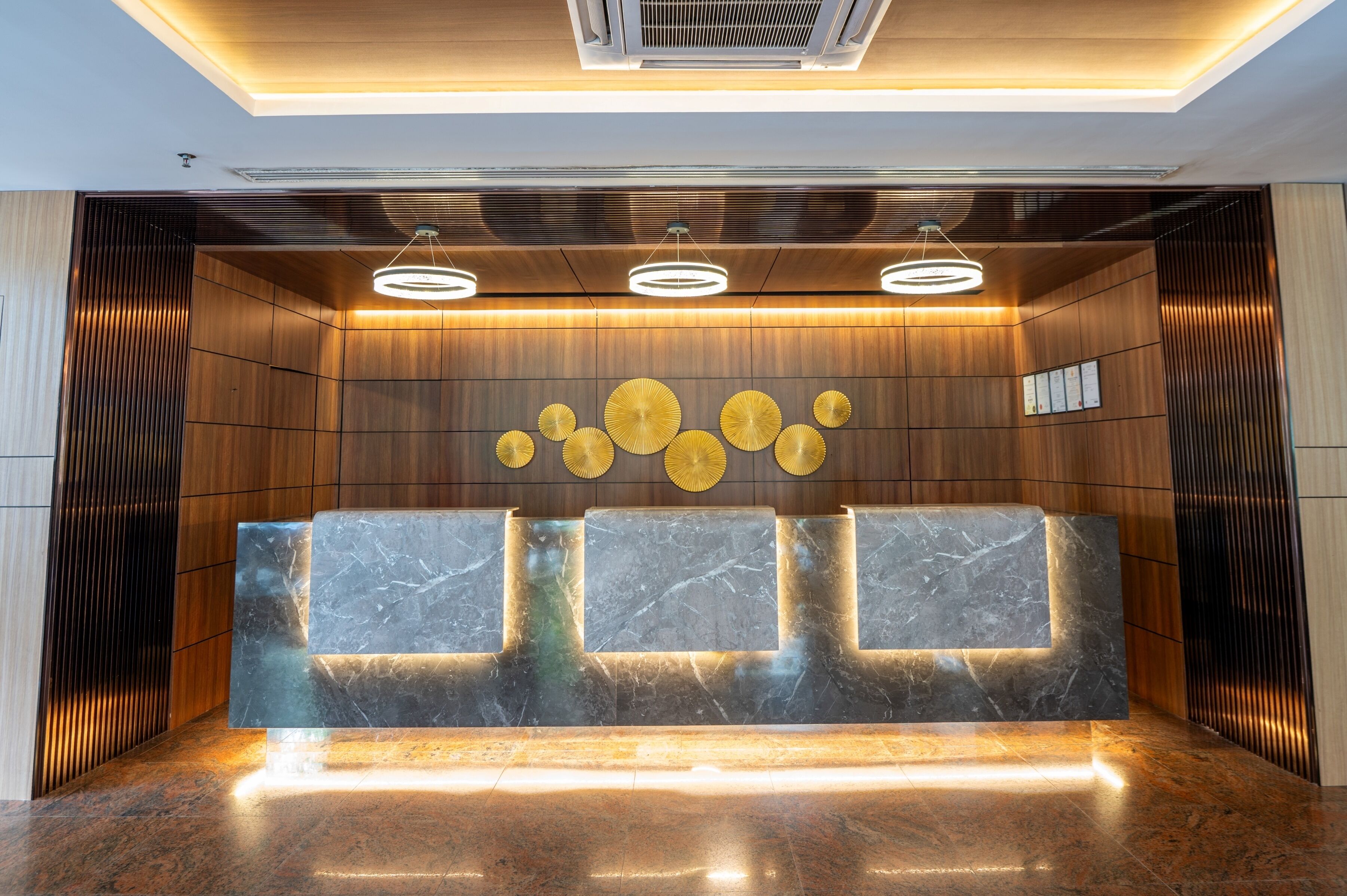 A reception area with a marble reception desk, wooden panel walls, and three pendant lights.