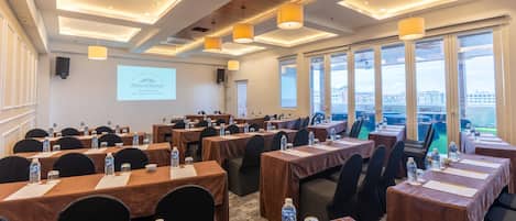 A conference room with tables, chairs, water bottles, and a presentation screen.