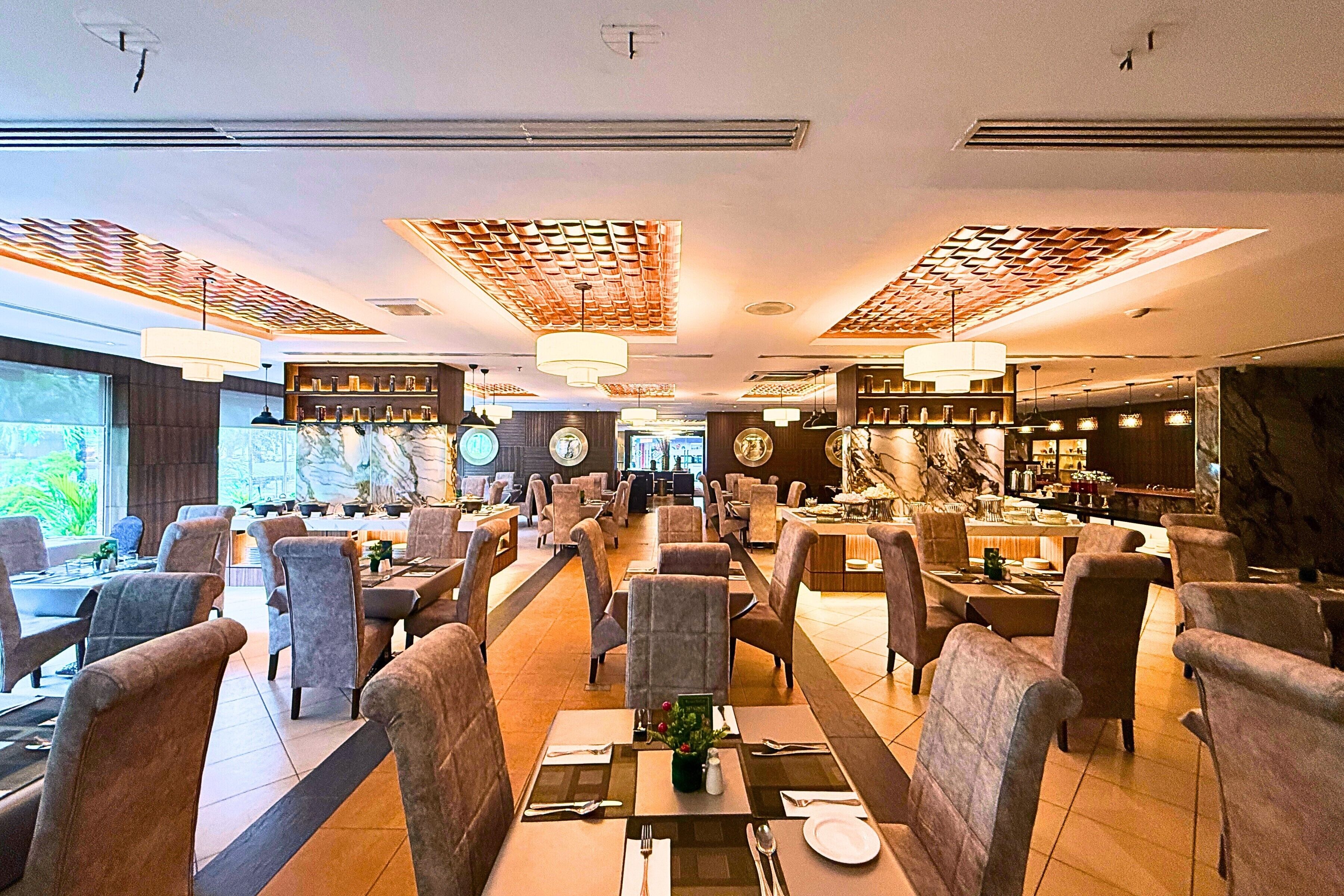 A spacious restaurant with high ceilings, modern lighting, and a variety of seating arrangements.
