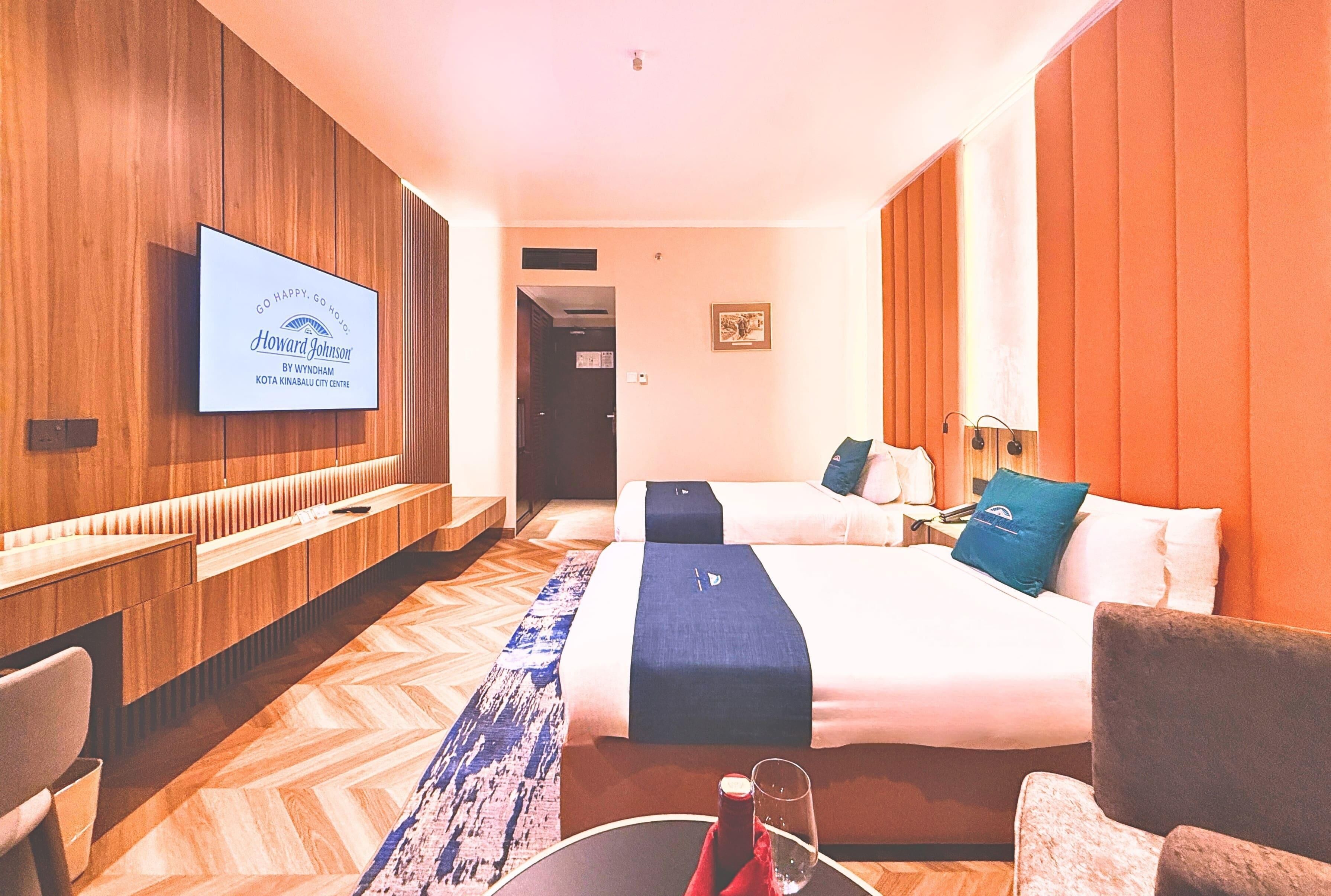 A hotel room with a bed, a desk, a TV, and a seating area.
