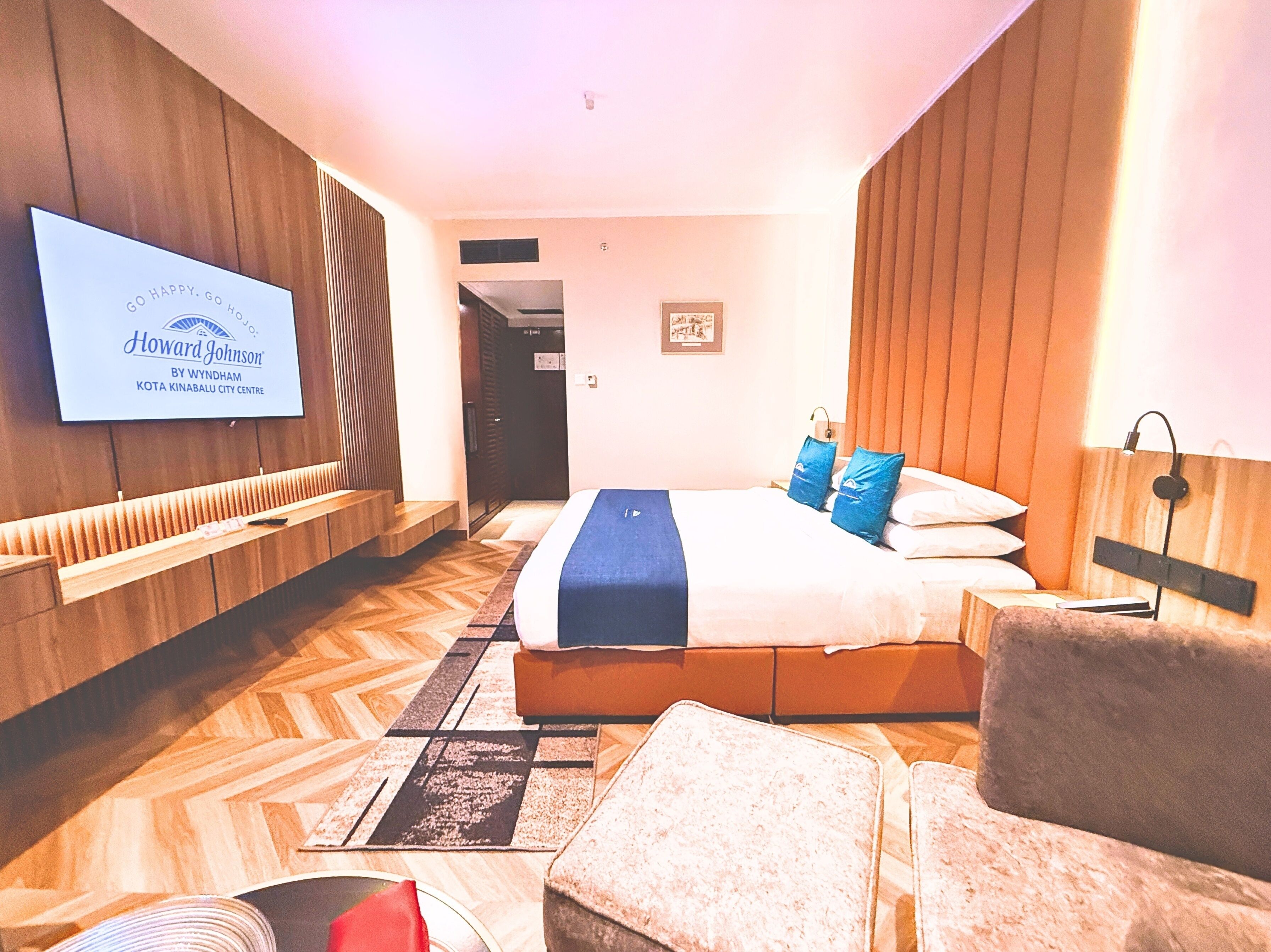 Ein modernes Hotelzimmer mit einem großen Bett, einem an der Wand montierten Fernseher und Wandverkleidung aus Holz.