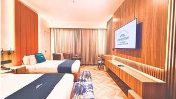 A hotel room with two beds, a TV, a desk, and a chair.