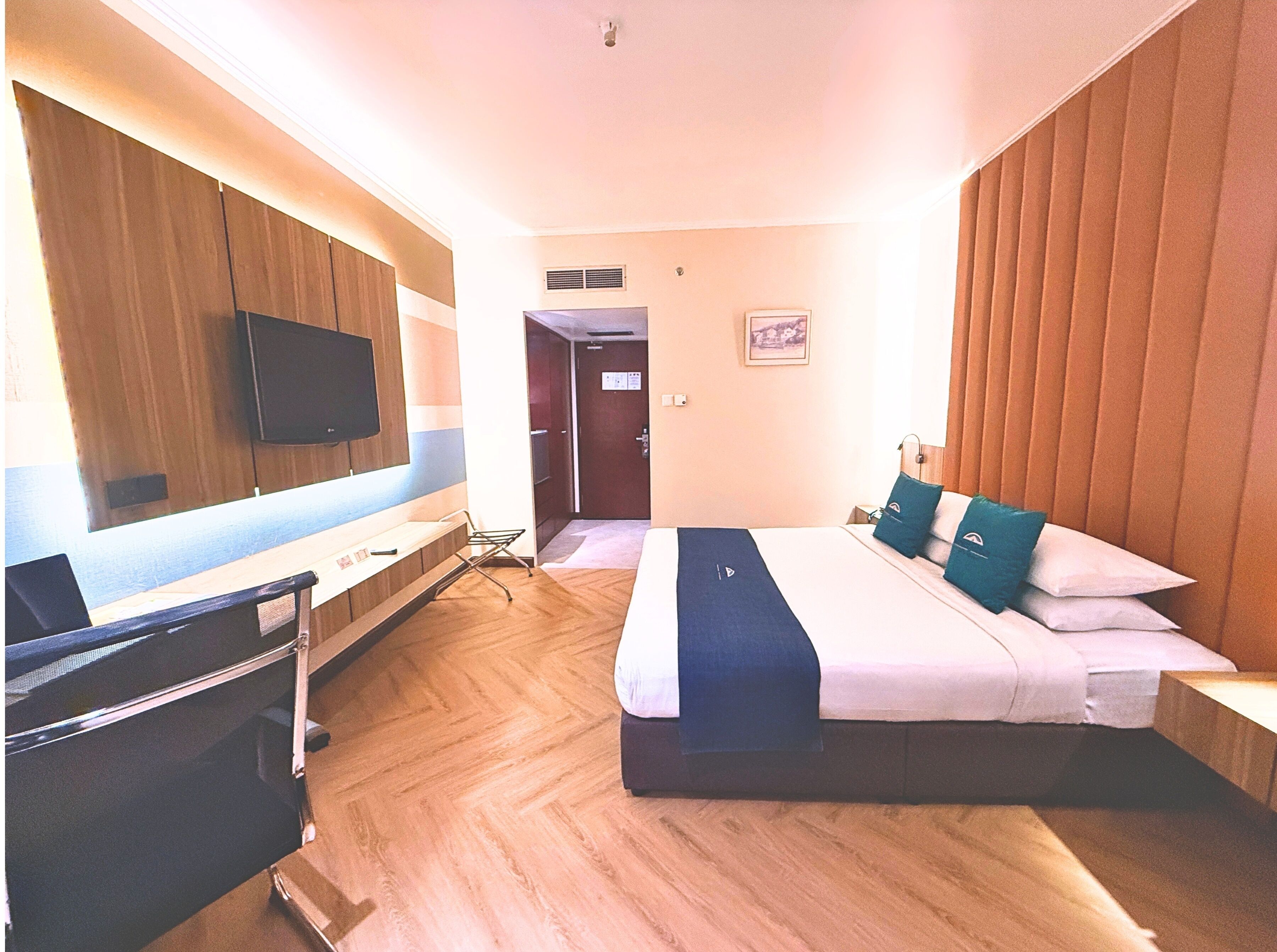Una habitación de hotel con cama, escritorio, silla, televisor y puerta.