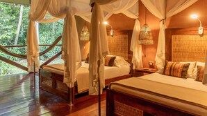 Una habitación con piso de madera, una cama con dosel, una mesita de noche y una lámpara colgante.