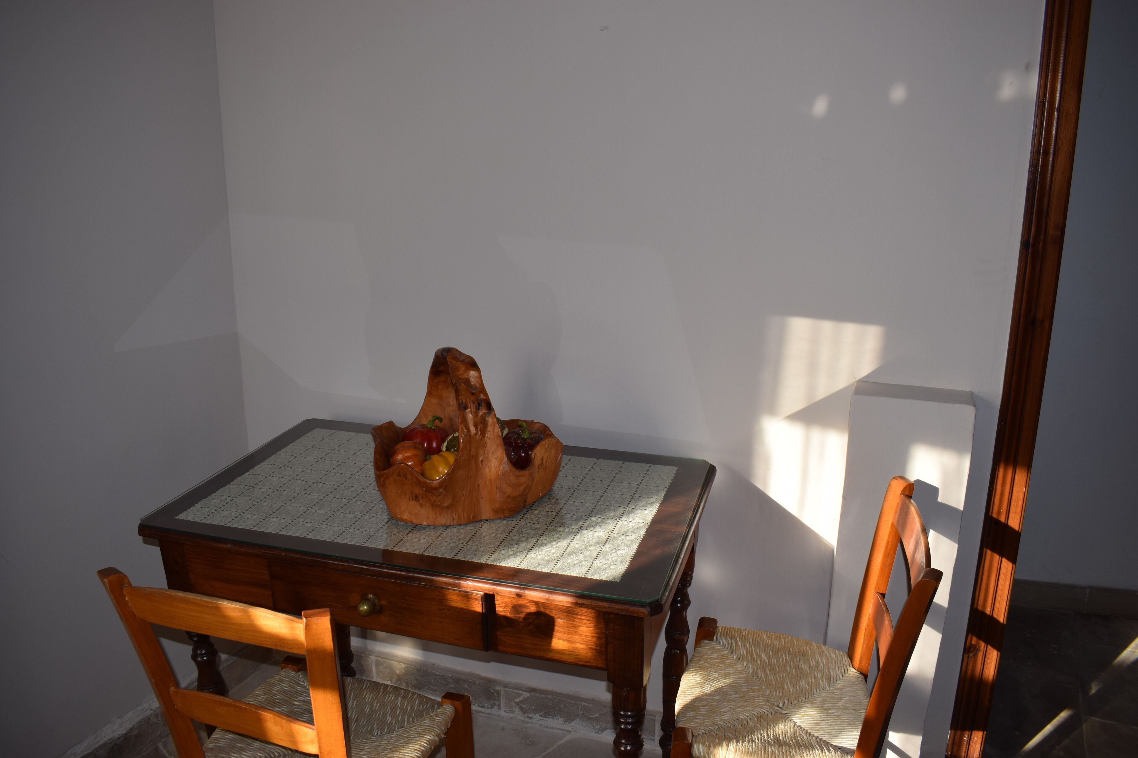 Una mesa de comedor de madera con un posavasos tejido y un centro de mesa de madera tallada.