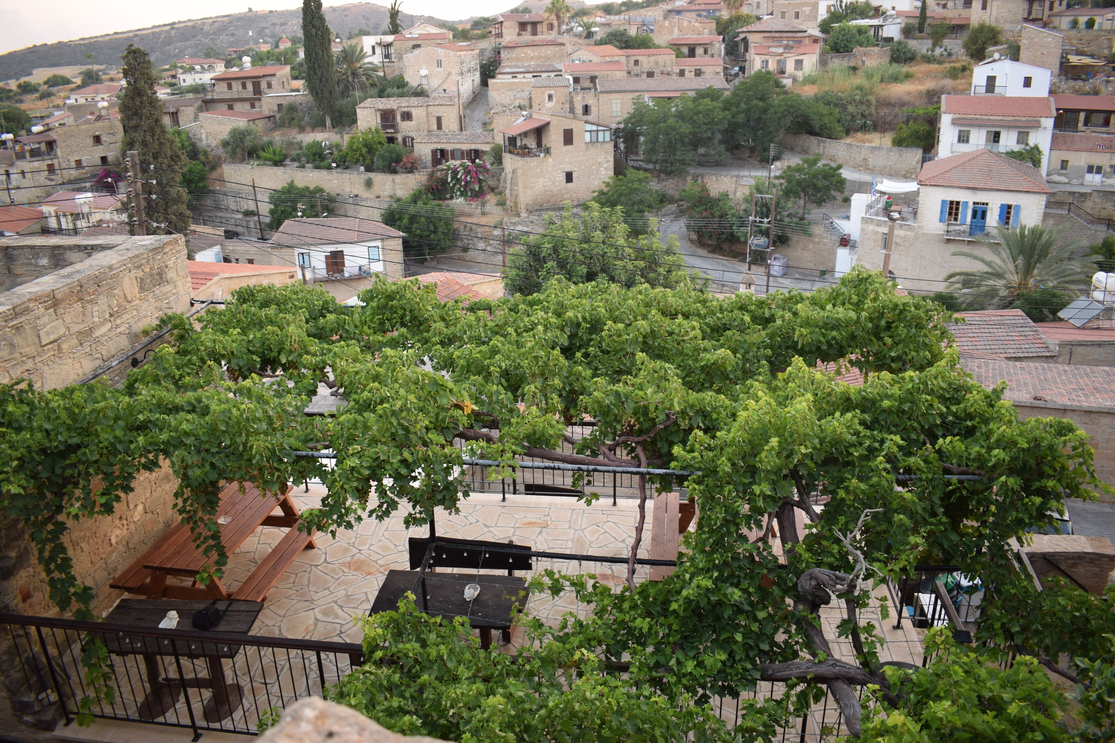 A courtyard with stone benches and tables, surrounded by buildings with traditional architecture.
