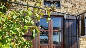 Un edificio in pietra con una porta in legno e gradini che conducono a un portico.