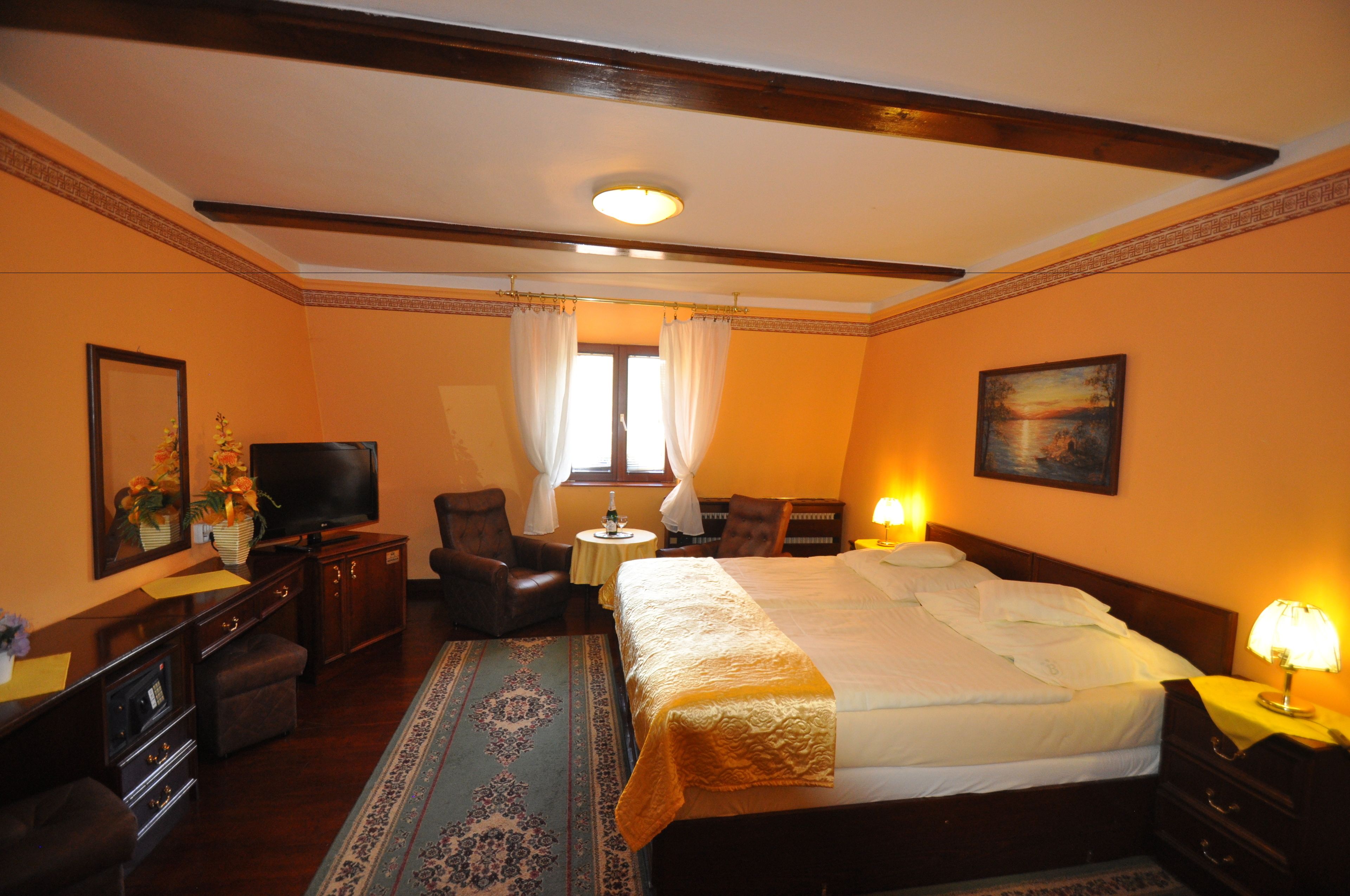 A hotel room with a large bed, a television, a desk, a chair, and a window with curtains.