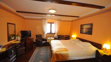 A hotel room with a large bed, a television, a desk, a chair, and a window with curtains.