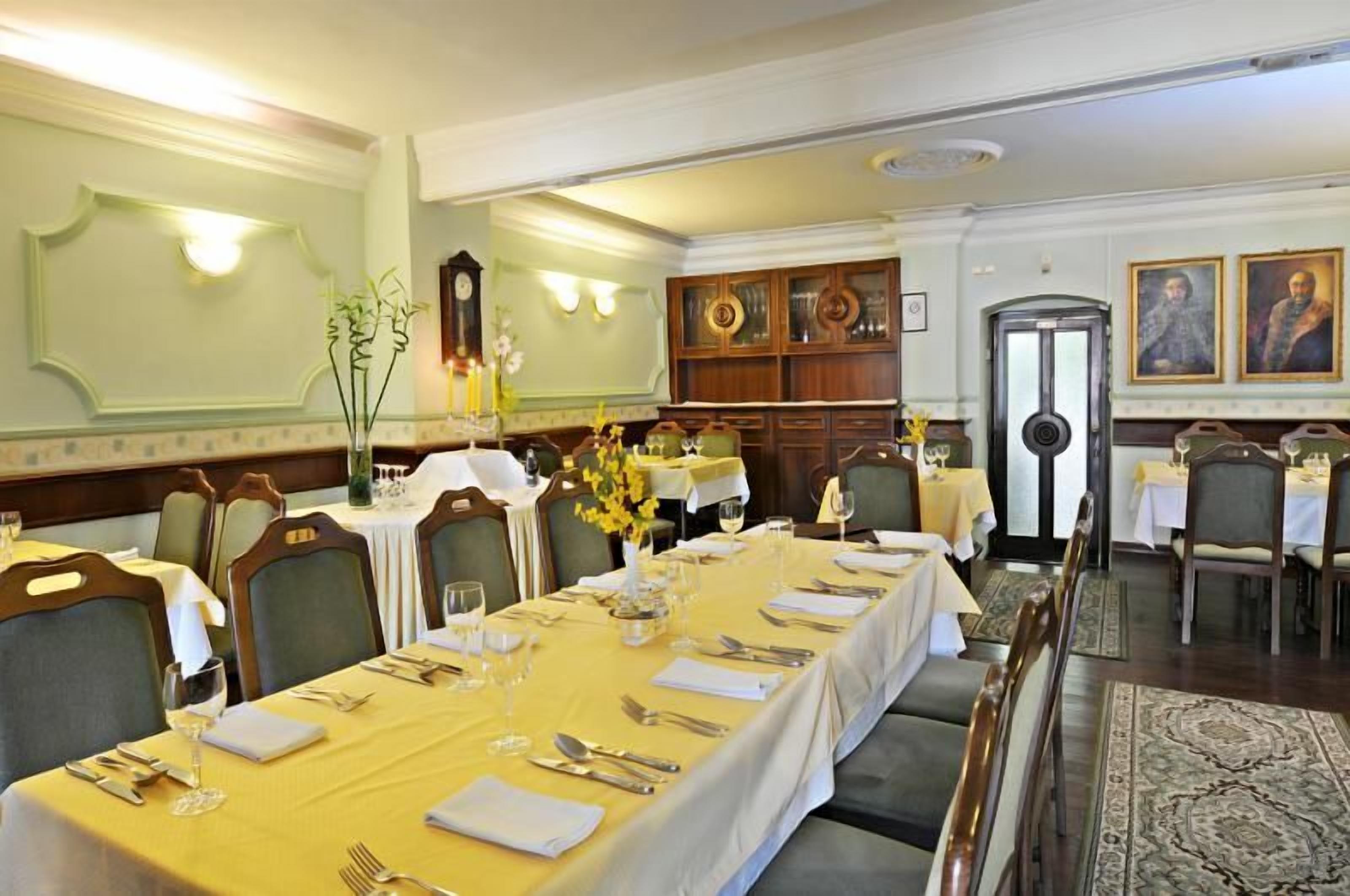A formal dining room with long tables set for a meal, wooden paneling, and traditional decor.