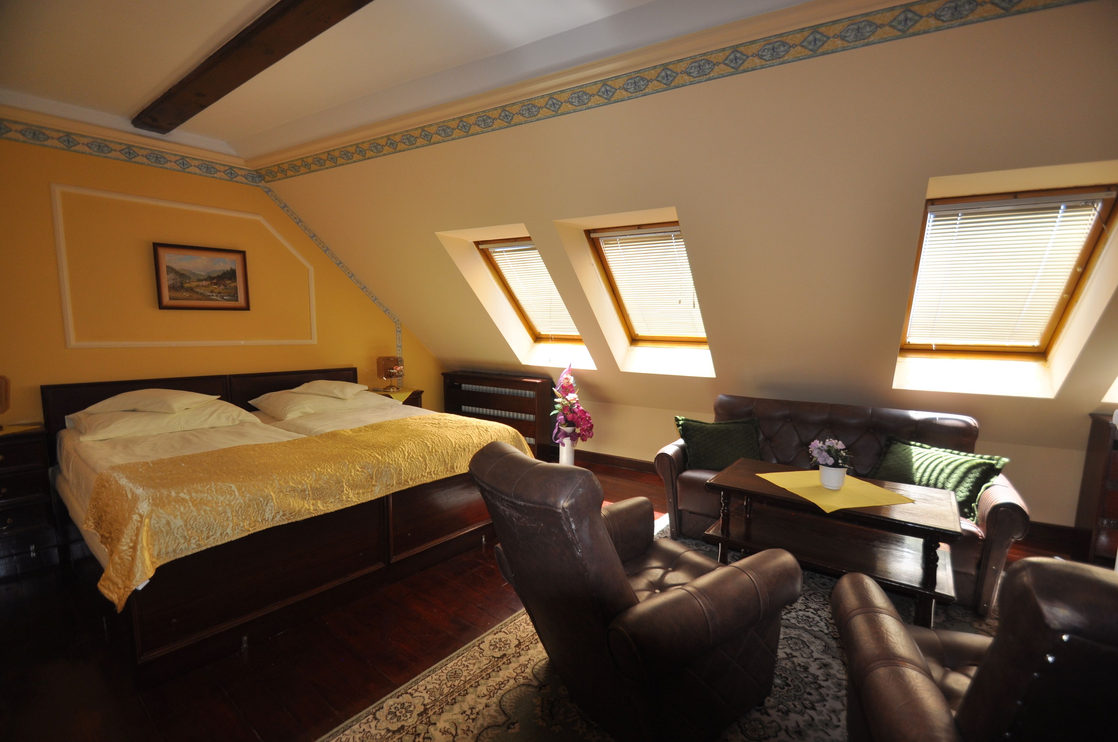 Un dormitorio con cama, escritorio y dos ventanas.