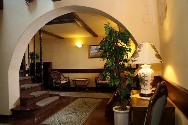 A cozy interior with a wooden staircase, a potted plant, a lamp, and a framed picture on the wall.