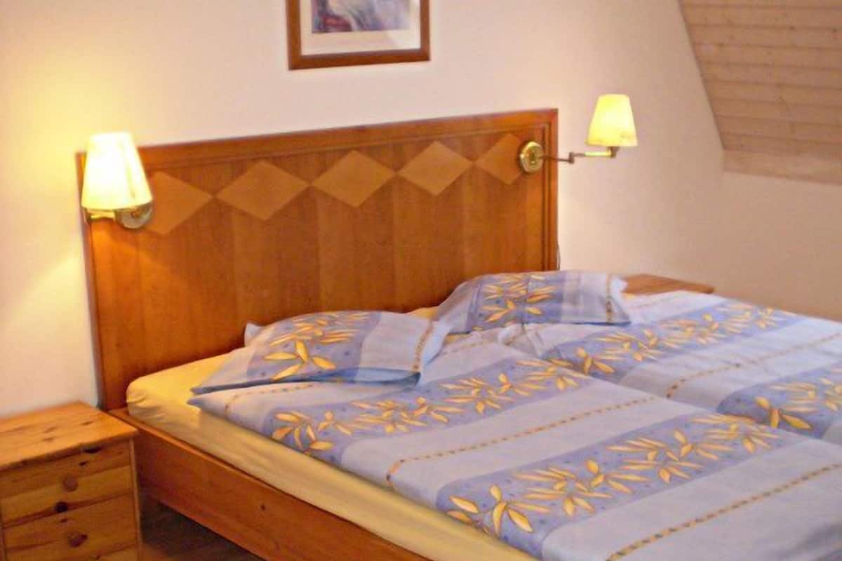Ein Schlafzimmer mit einem hölzernen Bett, zwei Nachttischlampen, einem Nachttisch und einem Bild an der Wand.