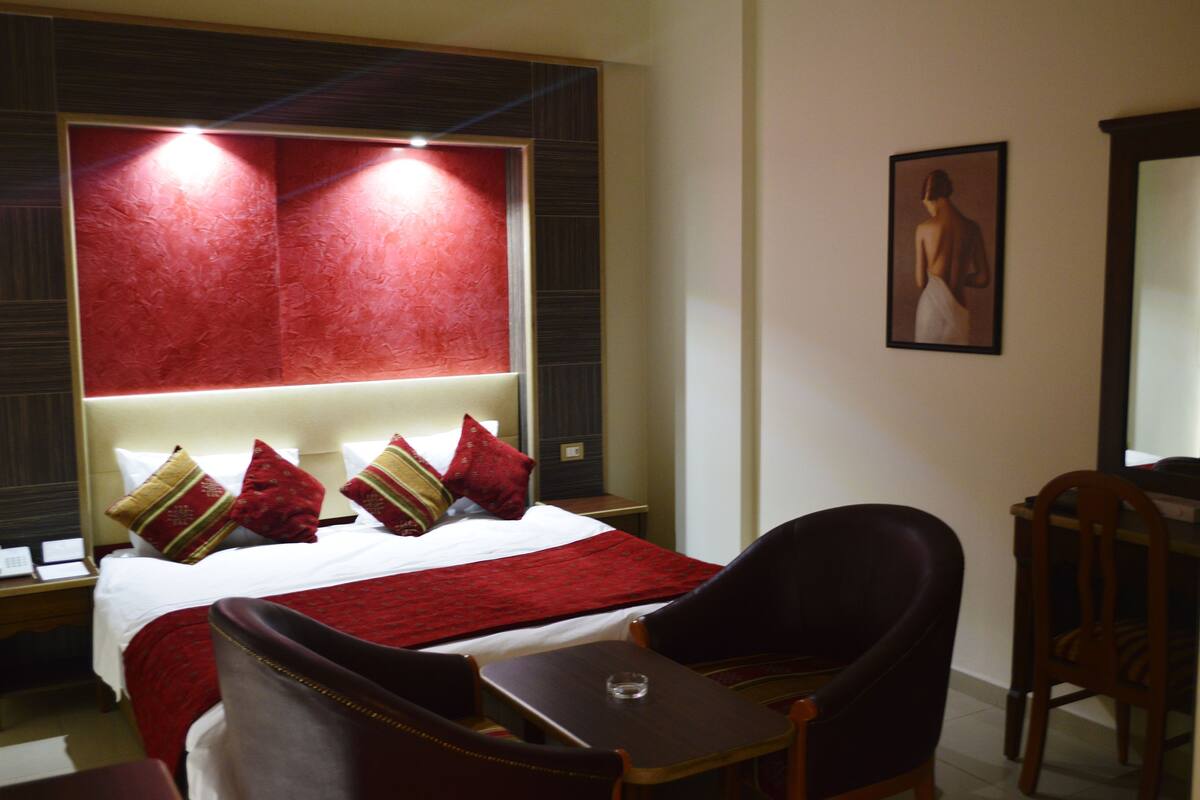 Una habitación de hotel con una cama grande, un escritorio y una silla.