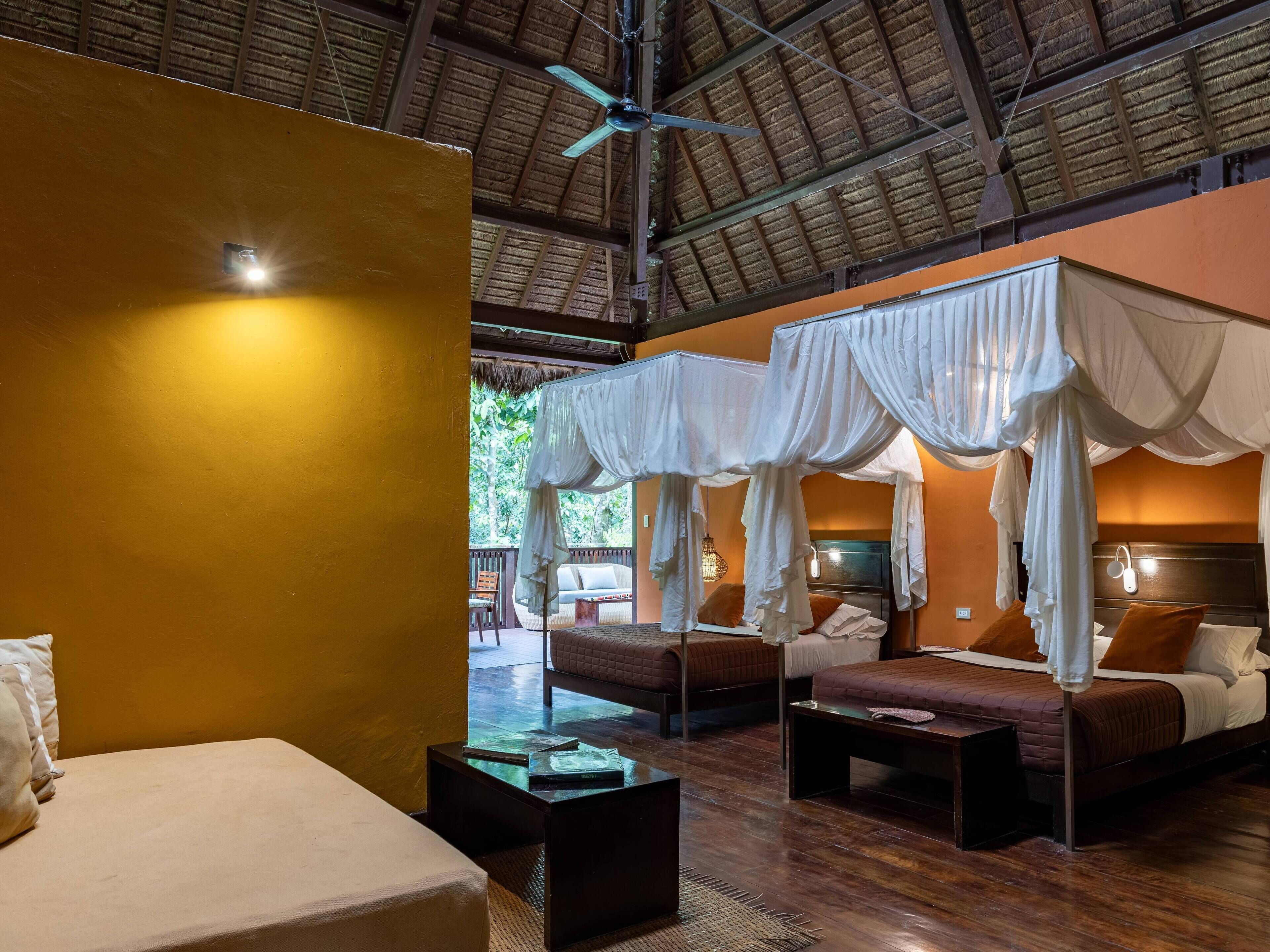 A room with a bed, a sofa, a small table, and a ceiling fan.