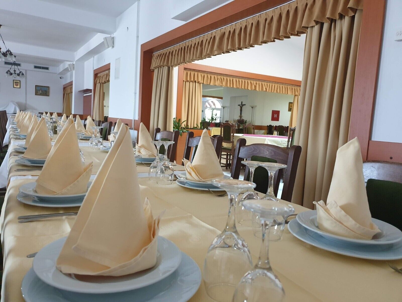 A dining area with tables set for a meal, featuring neatly folded napkins and wine glasses.