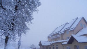 A snow-covered residential area with houses, a road, and a sign. - Hotel Mirni Kutak (Otocac)