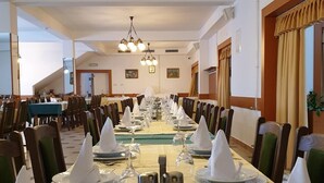 A banquet hall with long tables set for a formal event, featuring chandeliers and framed artwork on the walls. - Hotel Mirni Kutak (Otocac)