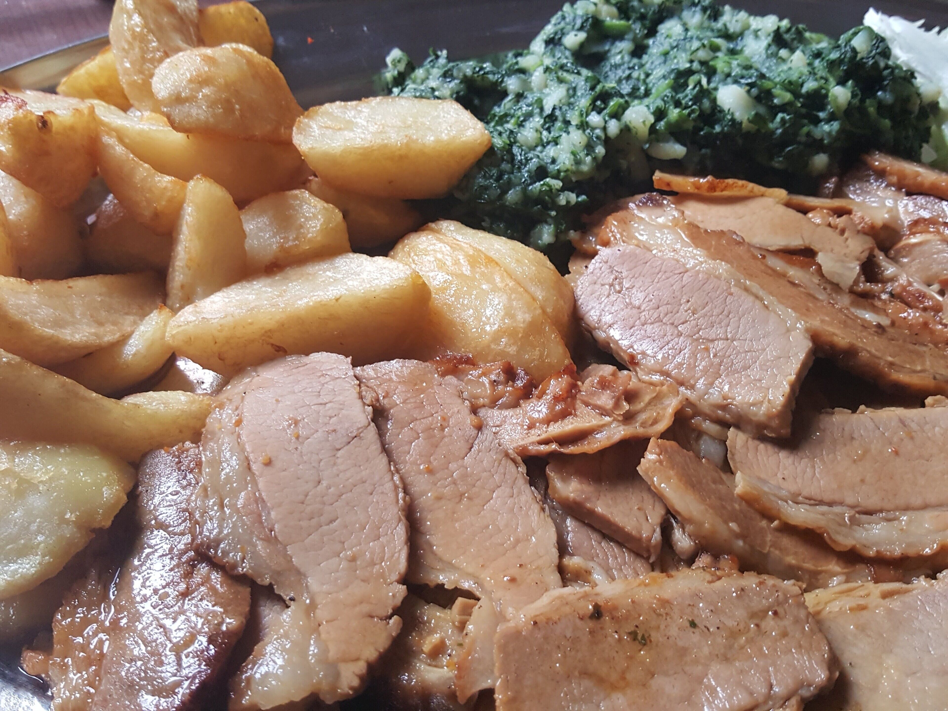 A plate of sliced roast beef, roasted potatoes, and steamed broccoli.