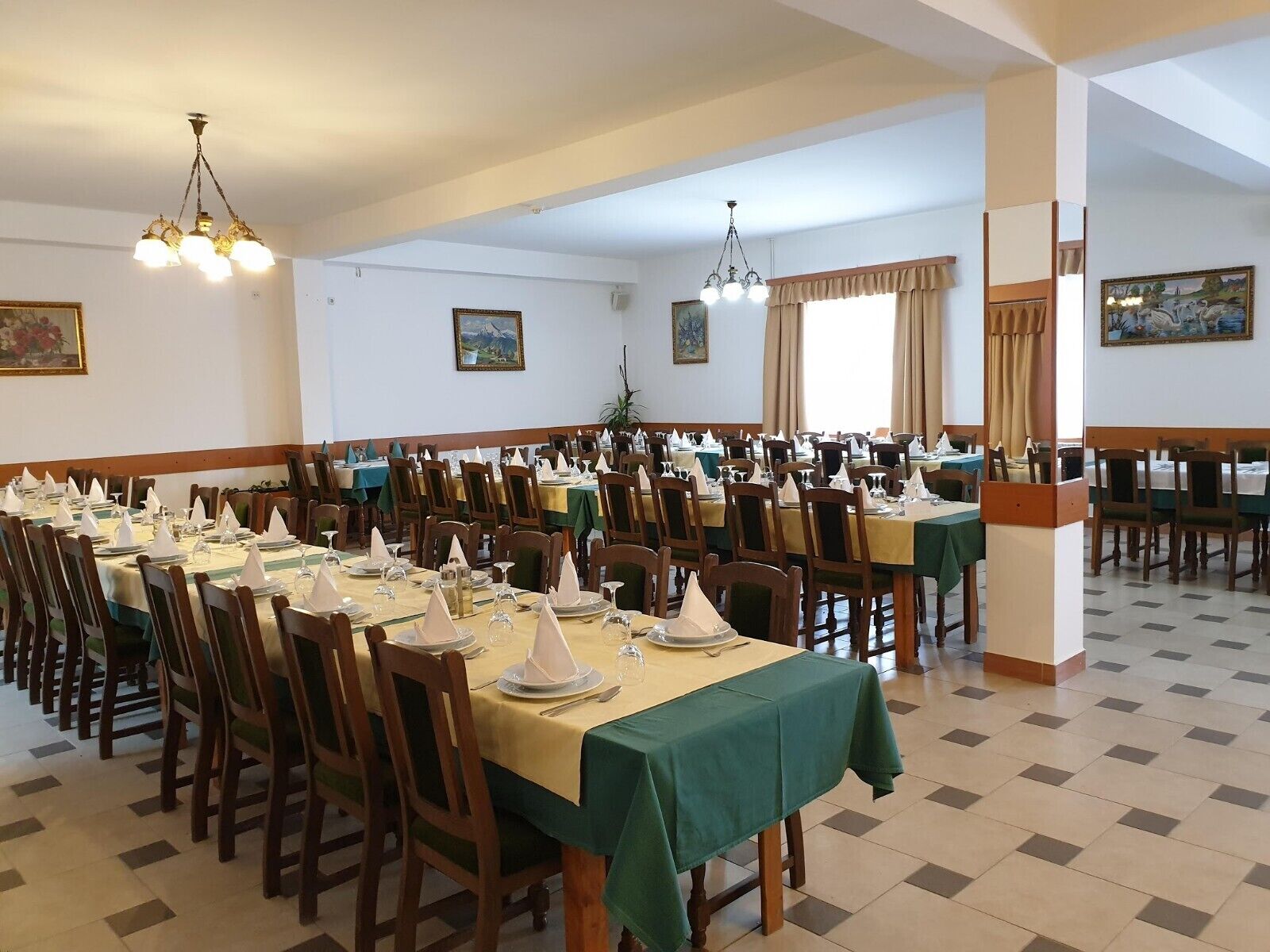 Un amplio comedor con varias mesas dispuestas para comidas, sillas de madera y candelabros.