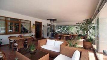 A spacious indoor area with wicker furniture, a white sofa, and a dining table.