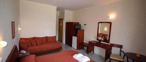 A hotel room with two beds, a desk, a chair, a dresser, and a mirror.