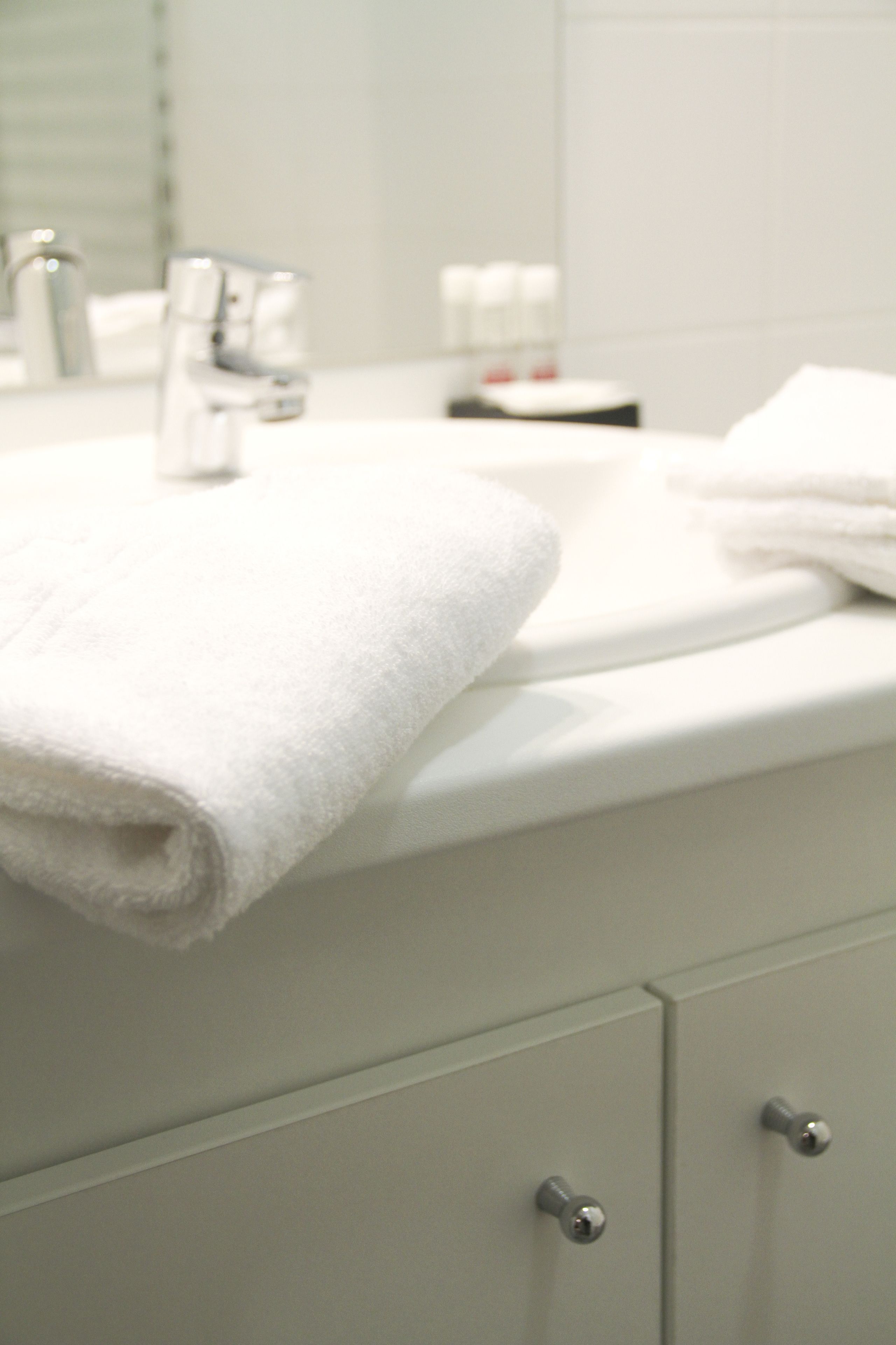 A bathroom with a white sink, a towel, and a mirror.