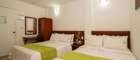 A hotel room with two beds, a desk, a chair, a mirror, and a nightstand with a vase of flowers.