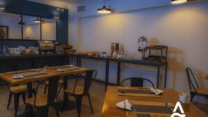 Un comedor con mesas y sillas de madera, un mostrador de buffet y una zona de cocina con electrodomésticos.