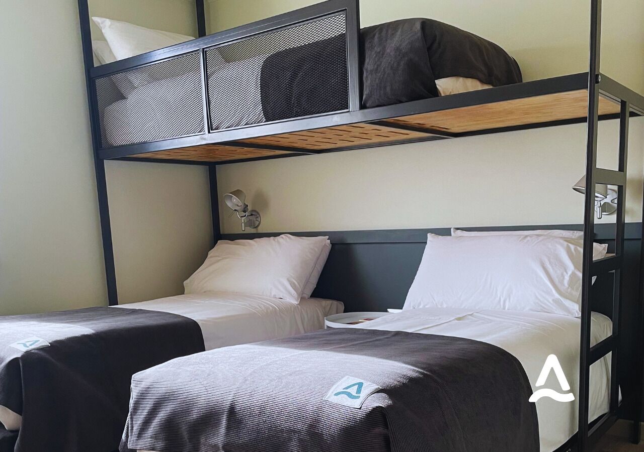 Habitación con literas, dos camas, cada una con almohada y manta.