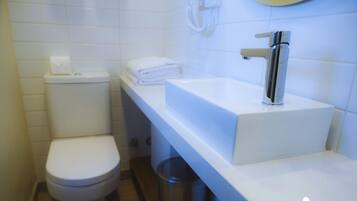 A modern bathroom with a toilet, sink, and trash bin.